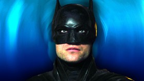 Robert Pattinson as Batman in his mask looking at the screen in The Batman.