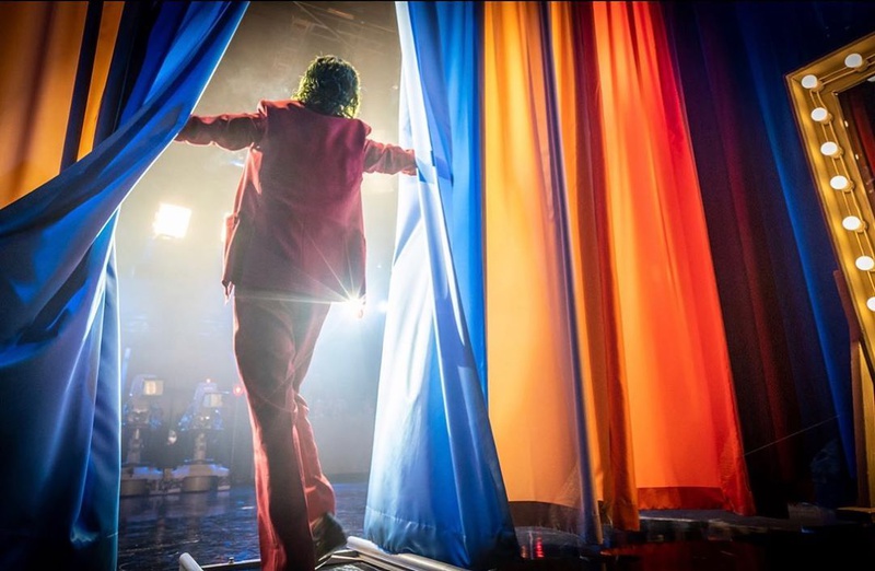 Joaquin Phoenix as Joker emerging from backstage curtains